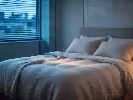 Modernes Schlafzimmer bei Dämmerung mit kühler Beleuchtung und atmungsaktiver Bettwäsche zur Schlafoptimierung. - Foto: über boerse-global.de