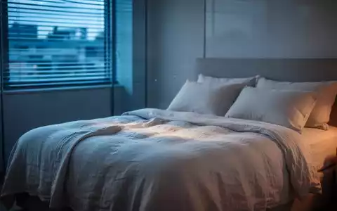Modernes Schlafzimmer bei Dämmerung mit kühler Beleuchtung und atmungsaktiver Bettwäsche zur Schlafoptimierung. - Foto: über boerse-global.de