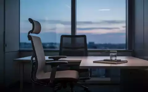 Ein leerer, minimalistischer Arbeitsplatz in einem modernen Büro bei Dämmerung, der Ruhe und Reflexion symbolisiert. - Foto: über boerse-global.de