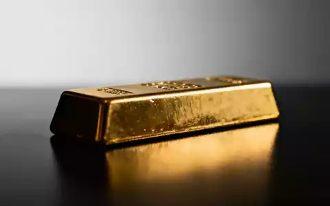 Ein einzelner Goldbarren auf einer dunklen, reflektierenden Oberfläche bei gedimmter Beleuchtung. - Foto: über boerse-global.de