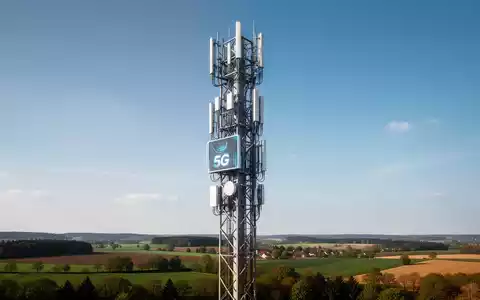 Moderner 5G-Mobilfunkmast vor einem klaren blauen Himmel in einer deutschen Landschaft. - Foto: über boerse-global.de