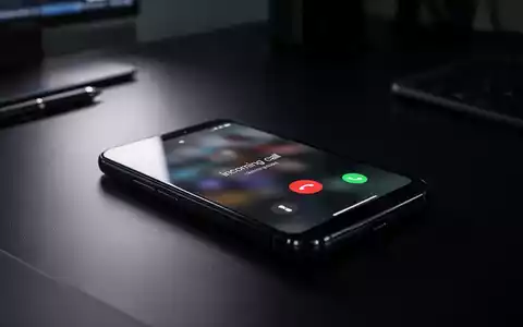 Ein Smartphone liegt auf einem dunklen Schreibtisch und symbolisiert die Gefahr durch betrügerische Anrufe. - Foto: über boerse-global.de