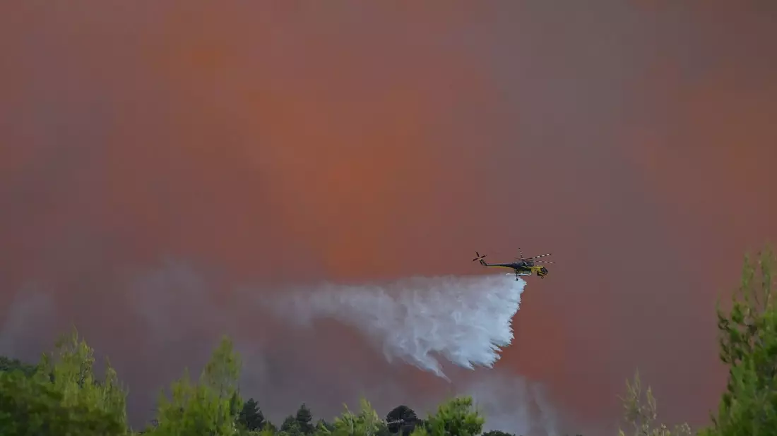 Es dürfte der einzige Hubschrauber gewesen sein, der es wagte: Starke Winde machten die Löscharbeiten aus der Luft unmöglich. - Bild: Michael Varaklas/AP/dpa
