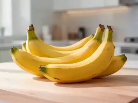 Frische Bananen auf einem hellen Holztisch in einer modernen Küche bei natürlichem Licht. - Foto: über boerse-global.de