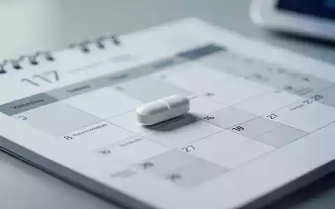 Eine einzelne Tablette auf einem Kalender zur Symbolisierung der wöchentlichen Medikamenteneinnahme bei Diabetes. - Foto: über boerse-global.de