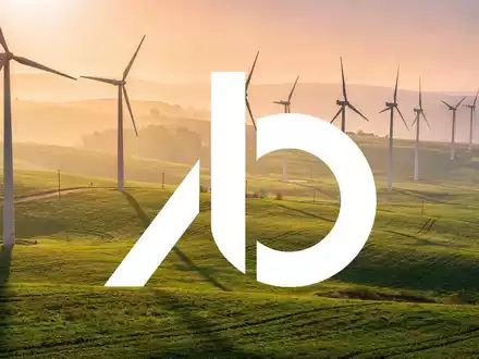 Moderne Windkraftanlagen in einer grünen Landschaft bei Sonnenuntergang als Symbol für erneuerbare Energien. - Foto: über boerse-global.de