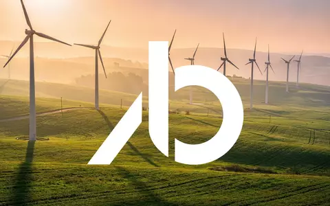 Moderne Windkraftanlagen in einer grünen Landschaft bei Sonnenuntergang als Symbol für erneuerbare Energien. - Foto: über boerse-global.de