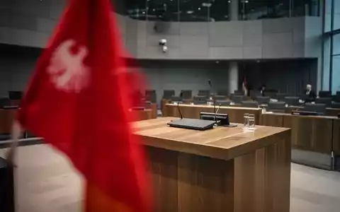 Ein verschwommenes rotes Parteisymbol vor einer parlamentarischen Kulisse, das eine angespannte politische Stimmung vermittelt. - Foto: über boerse-global.de