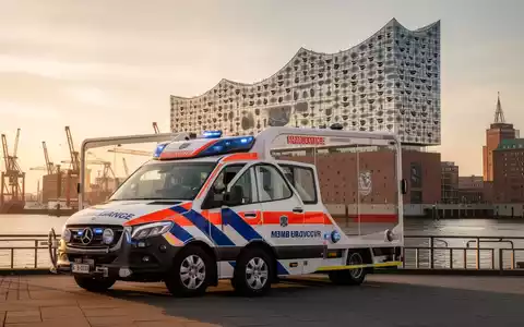 Ein Rettungswagen des ASB vor der Kulisse des Hamburger Hafens bei Sonnenuntergang. - Foto: über boerse-global.de