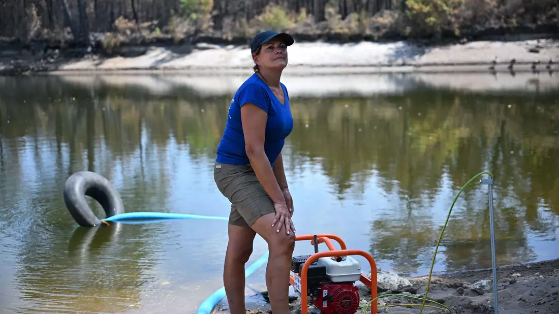 Maud hilft Freiwilligen, ihre Wassertanks zu befüllen. - Bild: Katharina Kausche/dpa
