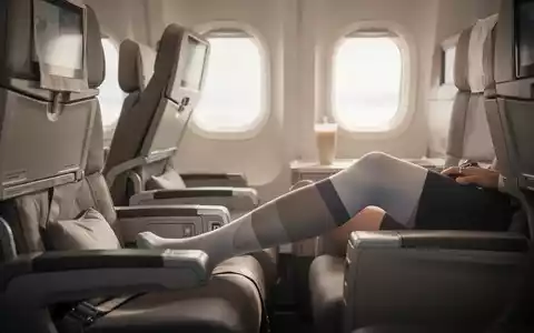 Passagier im Flugzeug trägt Kompressionsstrümpfe zur Vorbeugung von Thrombosen während eines Langstreckenflugs. - Foto: über boerse-global.de