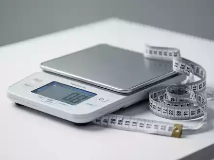 Eine digitale Personenwaage und ein Maßband auf einer sauberen, weißen Oberfläche als Symbol für Gesundheitsprävention. - Foto: über boerse-global.de