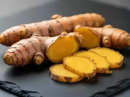 Frische Kurkuma- und Ingwerwurzeln auf einer dunklen Schieferplatte zur Veranschaulichung entzündungshemmender Ernährung. - Foto: über boerse-global.de