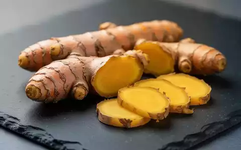 Frische Kurkuma- und Ingwerwurzeln auf einer dunklen Schieferplatte zur Veranschaulichung entzündungshemmender Ernährung. - Foto: über boerse-global.de