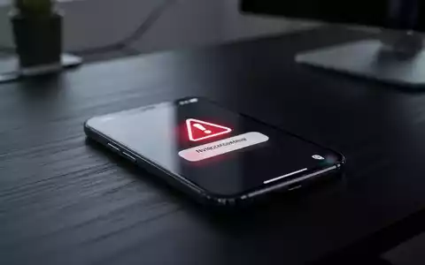 Smartphone-Bildschirm mit digitalem Sicherheitswarnsymbol auf dunklem Schreibtisch, Symbol für Online-Finanzbetrug. - Foto: über boerse-global.de
