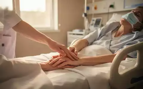 Eine Pflegekraft führt sanft eine Akupressur an der Hand eines Patienten in einer palliativmedizinischen Umgebung durch. - Foto: über boerse-global.de