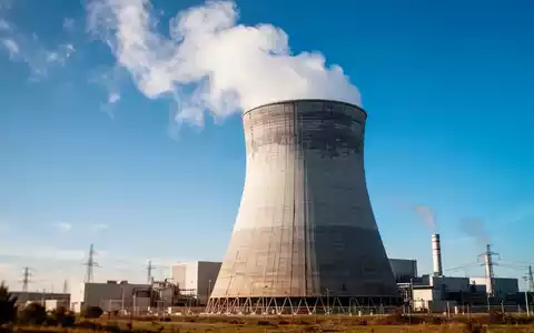 Modernes Kernkraftwerk mit Kühlturm bei klarem blauem Himmel als Symbol für den Uran-Sektor. - Foto: über boerse-global.de