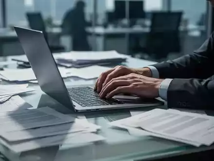 Ein moderner, unordentlicher Schreibtisch mit Laptop und Dokumenten, der den Stress und die Arbeitsbelastung im Büro symbolisiert. - Foto: über boerse-global.de