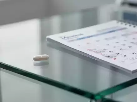 Eine einzelne Tablette liegt neben einem Kalenderblatt und symbolisiert den wöchentlichen Einnahmerhythmus bei HIV-Therapien. - Foto: über boerse-global.de