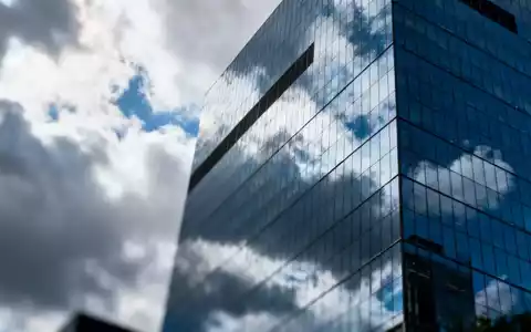 Moderne Glasfassade eines Bürogebäudes in einem Finanzviertel bei bewölktem Himmel. - Foto: über boerse-global.de