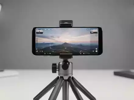 Modernes Smartphone auf Stativ mit KI-Fotobearbeitungs-Interface und Horizont-Erweiterungswerkzeugen. - Foto: über boerse-global.de