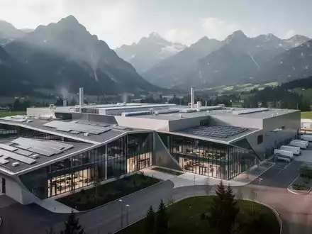 Moderner Industriestandort in Österreich vor einer alpinen Berglandschaft - Foto: über boerse-global.de