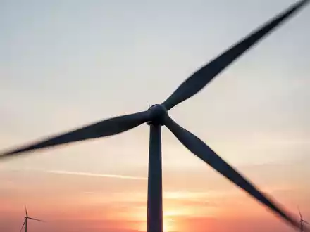 Silhouette einer Windkraftanlage vor einem Sonnenuntergang als Symbol für Rückenwind in der Industrie. - Foto: über boerse-global.de