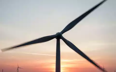 Silhouette einer Windkraftanlage vor einem Sonnenuntergang als Symbol für Rückenwind in der Industrie. - Foto: über boerse-global.de