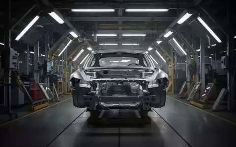 Ein einsames Autochassis in einer düster beleuchteten Montagehalle als Symbol für die Krise der Automobilindustrie. - Foto: über boerse-global.de