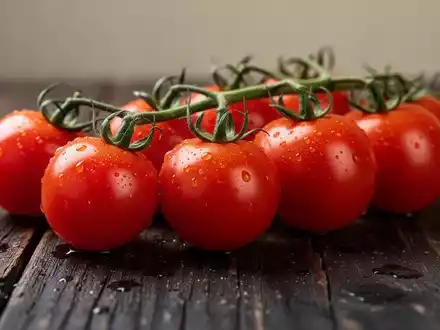 Frische, glänzende Cherrytomaten auf einem dunklen Holztisch in einer professionellen Food-Fotografie. - Foto: über boerse-global.de