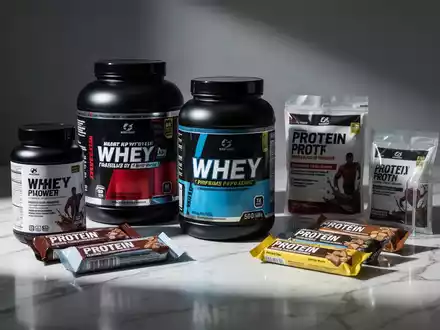 Protein-Supplemente wie Whey-Pulver und Riegel auf einem Labortisch vor neutralem Hintergrund. - Foto: über boerse-global.de