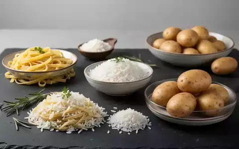 Nahaufnahme von verschiedenen Kohlenhydratbeilagen wie Nudeln, Reis und Kartoffeln auf einer dunklen Schieferplatte. - Foto: über boerse-global.de