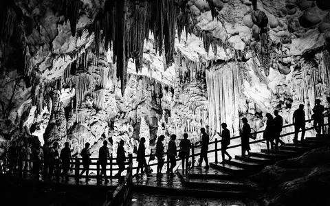 Schwarzweiss-Reportagebild vom Wahrzeichen Reed-Flute-Cave in Guilin China, dokumentarische Reisefotografie mit starken Kontrasten - Foto: THN
