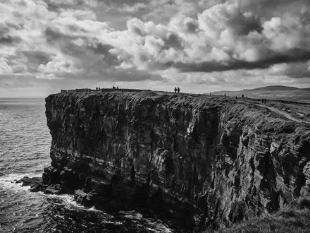 Schwarzweiss-Reportagebild vom Wahrzeichen Cliffs of Moher in Liscannor Irland, dokumentarische Reisefotografie mit starken Kontrasten - Foto: THN