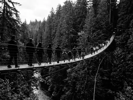 Schwarzweiss-Reportagebild vom Wahrzeichen Capilano Suspension Bridge in North Vancouver Kanada, dokumentarische Reisefotografie mit starken Kontrasten - Foto: THN