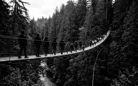 Schwarzweiss-Reportagebild vom Wahrzeichen Capilano Suspension Bridge in North Vancouver Kanada, dokumentarische Reisefotografie mit starken Kontrasten - Foto: THN