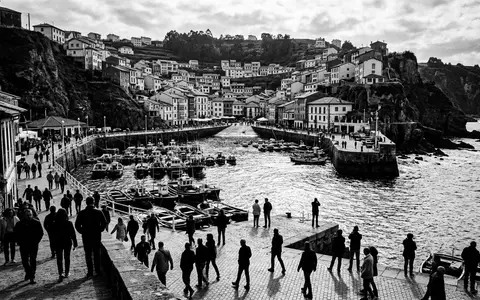 Schwarzweiss-Reportagebild vom Wahrzeichen Hafen von Cudillero in Cudillero Spanien, dokumentarische Reisefotografie mit starken Kontrasten - Foto: THN