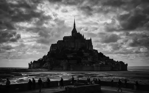 Schwarzweiss-Reportagebild vom Wahrzeichen Mont-Saint-Michel in Le Mont-Saint-Michel Frankreich, dokumentarische Reisefotografie mit starken Kontrasten - Foto: THN