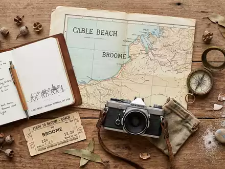 Flatlay-Reise-Arrangement rund um Cable Beach Broome in Broome Australien, Karte Kompass Kamera und generische Reiserequisiten - Foto: THN