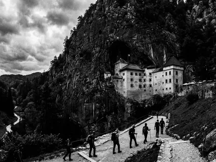 Schwarzweiss-Reportagebild vom Wahrzeichen Burg Predjama in Postojna Slowenien, dokumentarische Reisefotografie mit starken Kontrasten - Foto: THN