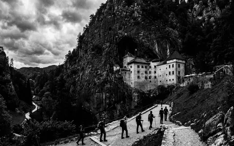 Schwarzweiss-Reportagebild vom Wahrzeichen Burg Predjama in Postojna Slowenien, dokumentarische Reisefotografie mit starken Kontrasten - Foto: THN