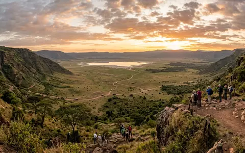 Fotorealistische Panoramaaufnahme von Ngorongoro-Krater in Ngorongoro Tansania, warmes Abendlicht auf Wahrzeichen im Reisemotiv - Foto: THN