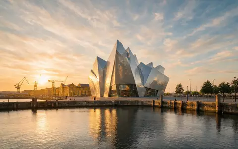 Fotorealistische Panoramaaufnahme von Titanic Belfast in Belfast Vereinigtes Königreich, warmes Abendlicht auf Wahrzeichen - Foto: THN