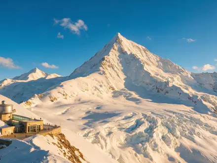 Fotorealistische Panoramaaufnahme von Jungfraujoch in Jungfraujoch Schweiz, warmes Abendlicht auf Wahrzeichen im Reisemotiv - Foto: THN