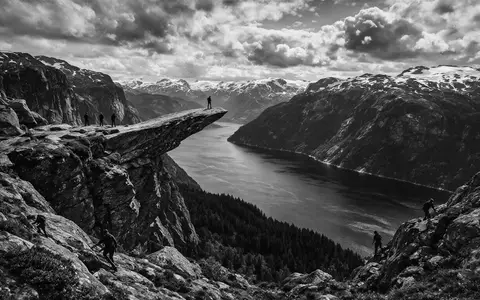 Schwarzweiss-Reportagebild vom Wahrzeichen Trolltunga in Ullensvang Norwegen, dokumentarische Reisefotografie mit starken Kontrasten - Foto: THN
