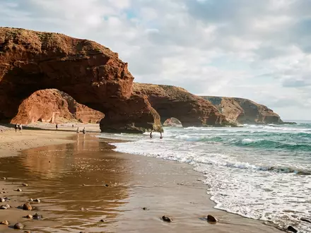 Editorialbild im Reisemagazin-Stil vom Wahrzeichen Legzira-Strand in Sidi Ifni Marokko, ausgewogene Bildgestaltung und natuerliches Umgebungslicht - Foto: THN
