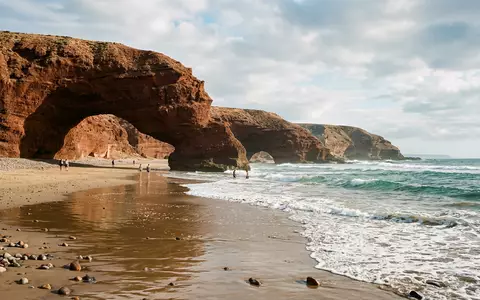 Editorialbild im Reisemagazin-Stil vom Wahrzeichen Legzira-Strand in Sidi Ifni Marokko, ausgewogene Bildgestaltung und natuerliches Umgebungslicht - Foto: THN