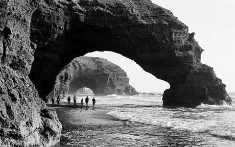 Schwarzweiss-Reportagebild vom Wahrzeichen Legzira-Strand in Sidi Ifni Marokko, dokumentarische Reisefotografie mit starken Kontrasten - Foto: THN