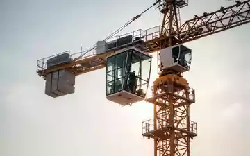 Ein moderner Baukran unter einem heißen Sommerhimmel mit Fokus auf die klimatisierte Führerkabine. - Foto: über boerse-global.de