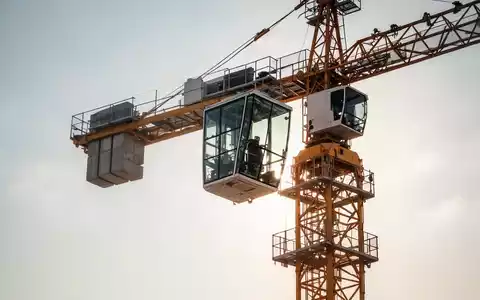 Ein moderner Baukran unter einem heißen Sommerhimmel mit Fokus auf die klimatisierte Führerkabine. - Foto: über boerse-global.de